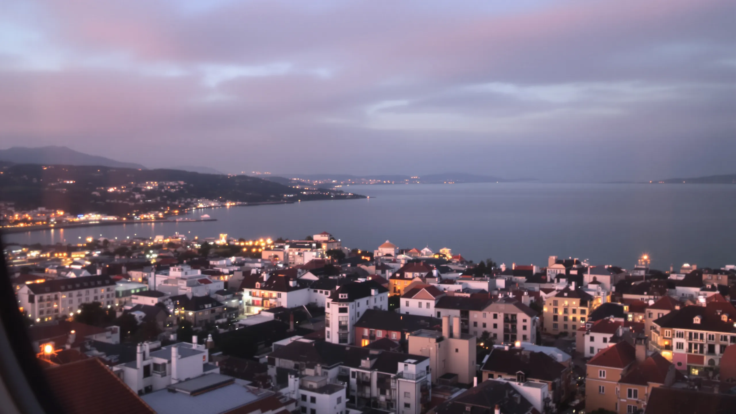 Blick über die Dächer einer Küstenstadt aufs Meer in der Abenddämmerung